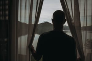Photographie du mont Fuji vu d'une chambre d'hôtel. Un homme est en premier plan en flou et le regarde